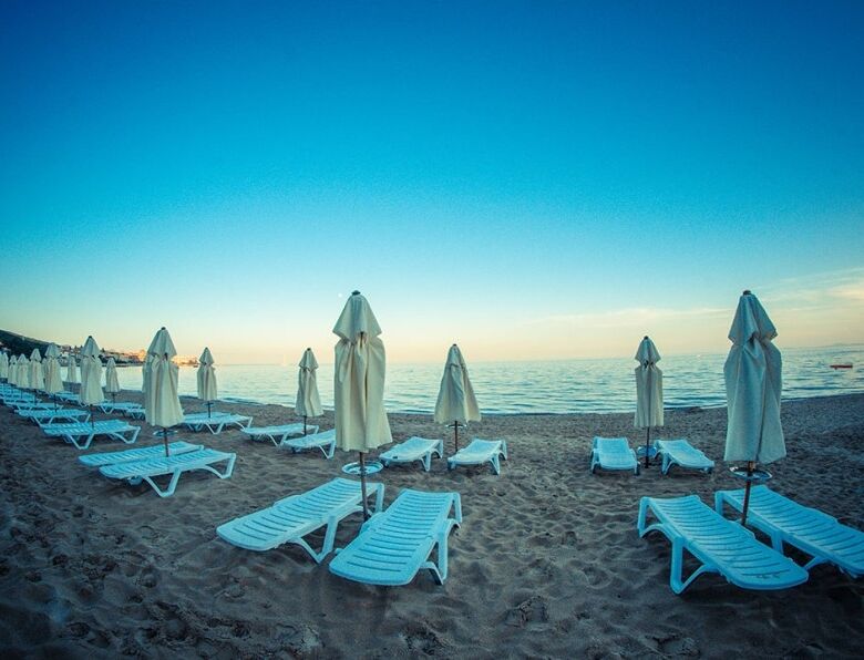 Bright beach scene with empty sunbeds and umbrellas overlooking the sea. Perfect for relaxing holida.