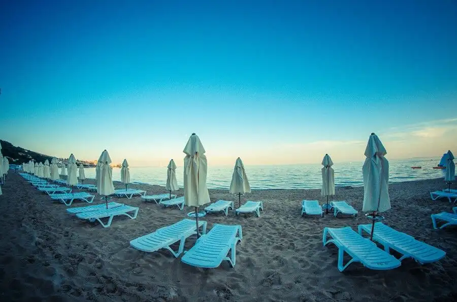 Bright beach scene with empty sunbeds and umbrellas overlooking the sea. Perfect for relaxing holida.