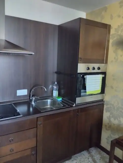 Kitchen with wooden cabinets, sink, oven, and countertop.