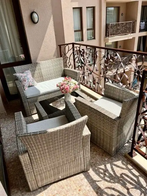 Balcony with wicker seating, floral centerpiece, and decorative railing overlooking Sunny Beach.