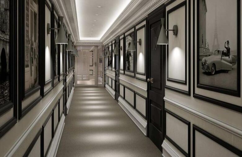 Bright hotel hallway featuring stylish black and white wall panels and soft lighting.