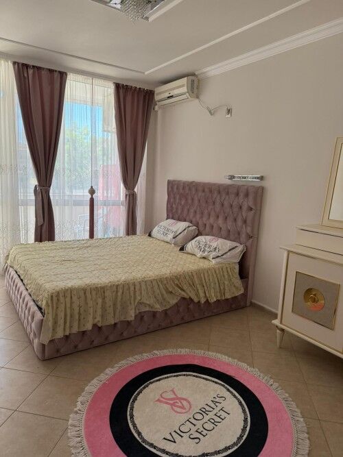 Bright bedroom with pink upholstered bed and elegant decor.