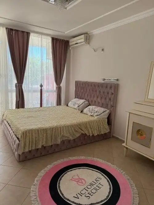 Bright bedroom with pink upholstered bed and elegant decor.