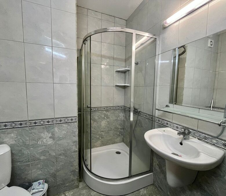 Interior view of a compact bathroom with shower, sink, and toilet in Karolina spa complex.