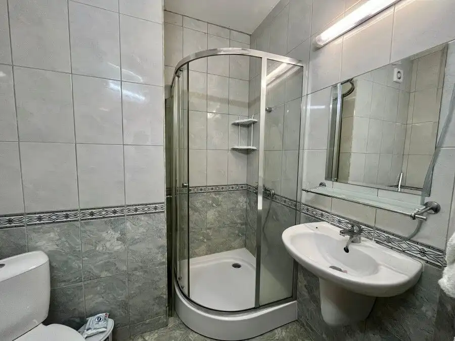 Interior view of a compact bathroom with shower, sink, and toilet in Karolina spa complex.