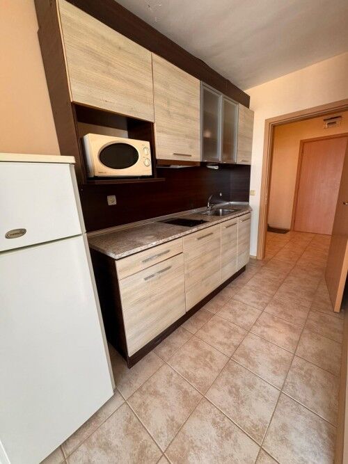 Compact kitchen with modern cabinets and microwave in a seaside apartment.