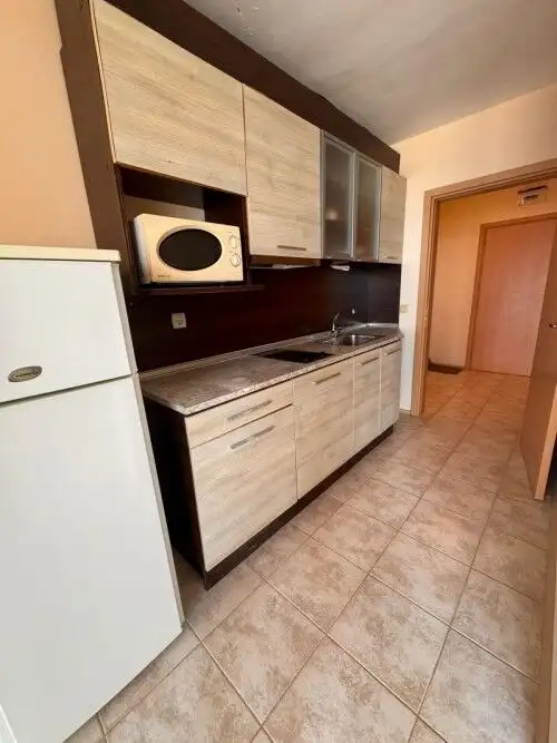 Compact kitchen with modern cabinets and microwave in a seaside apartment.