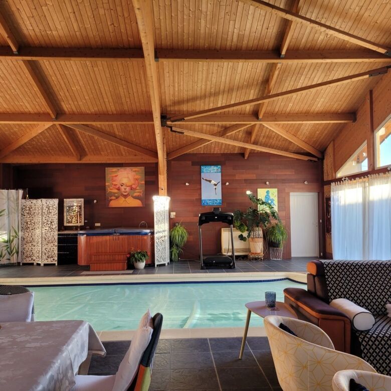 Indoor swimming pool with wooden ceiling and natural light in a spacious home.