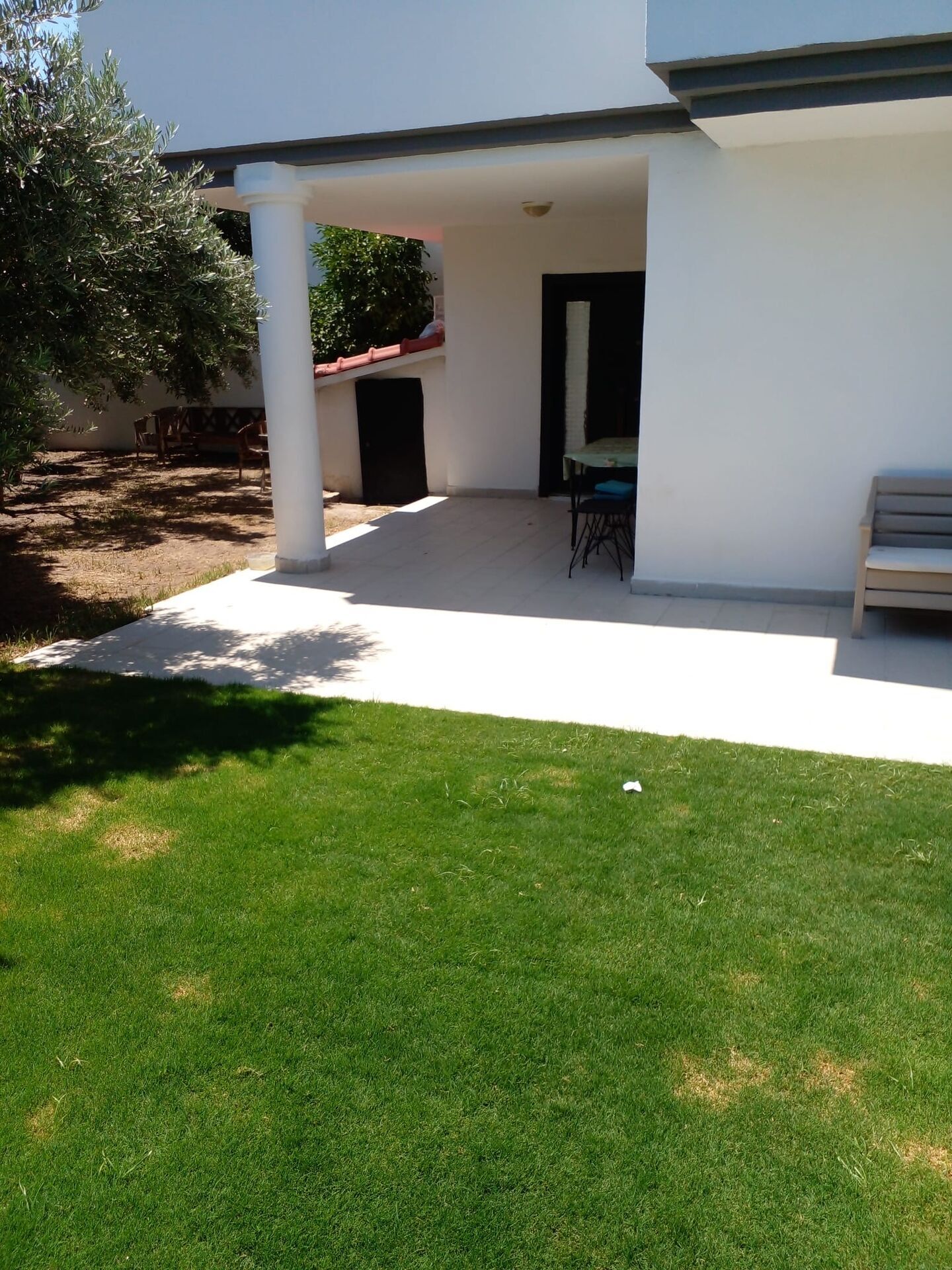 Modern villa outdoor patio with garden in Cesme, Turkey. Outdoor patio of a luxury villa with seating area and lush green lawn.