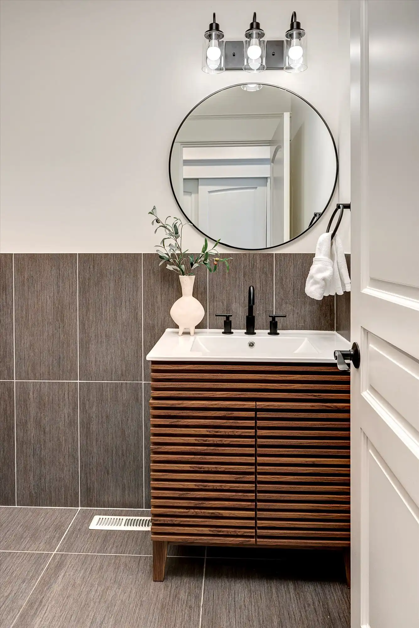 Modern bathroom with stylish vanity, round mirror, and elegant decor in a luxury lakefront home.