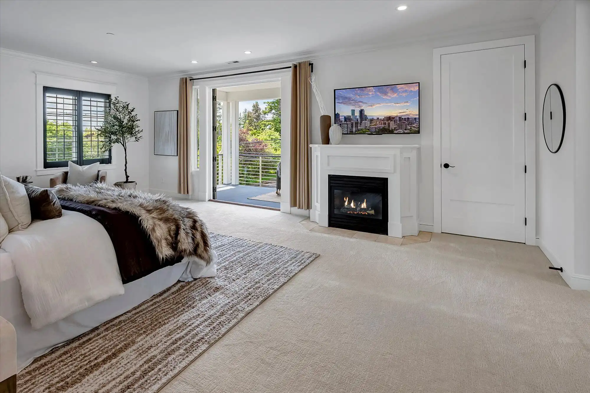 Elegant interior of a custom luxury home featuring a cozy fireplace, large windows, and a balcony ov.