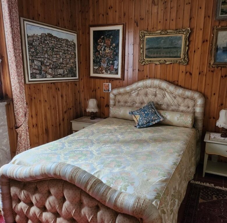 Elegant bedroom in a rustic country villa with vintage decor and artwork.