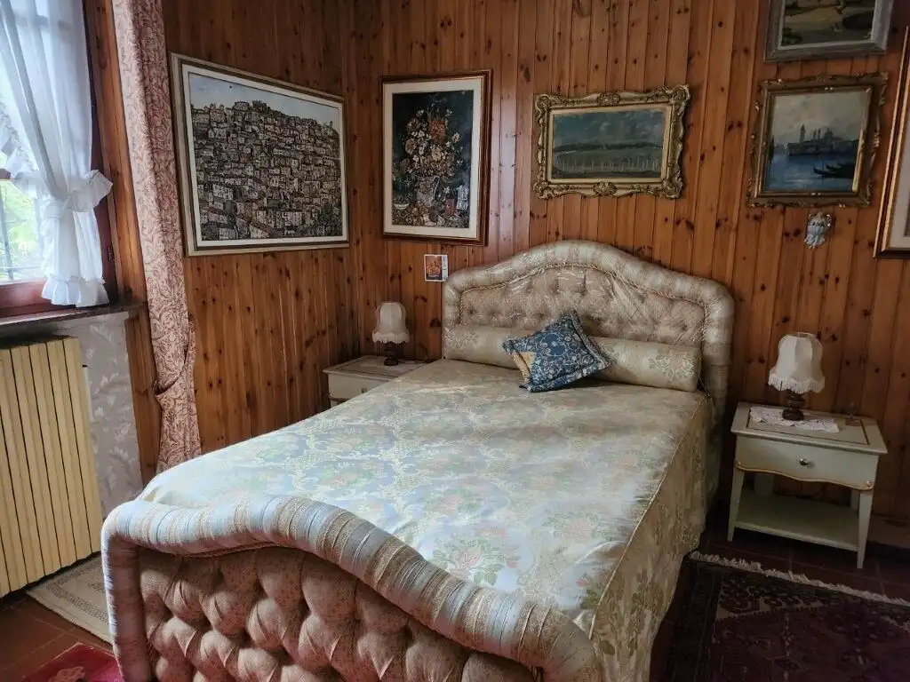 Elegant bedroom in a rustic country villa with vintage decor and artwork.