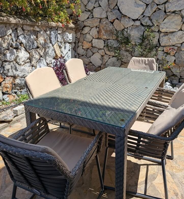 Outdoor dining table with six chairs in a cozy garden setting.