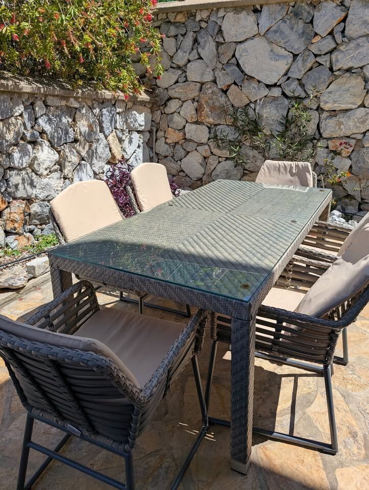 Outdoor dining table with six chairs in a cozy garden setting.