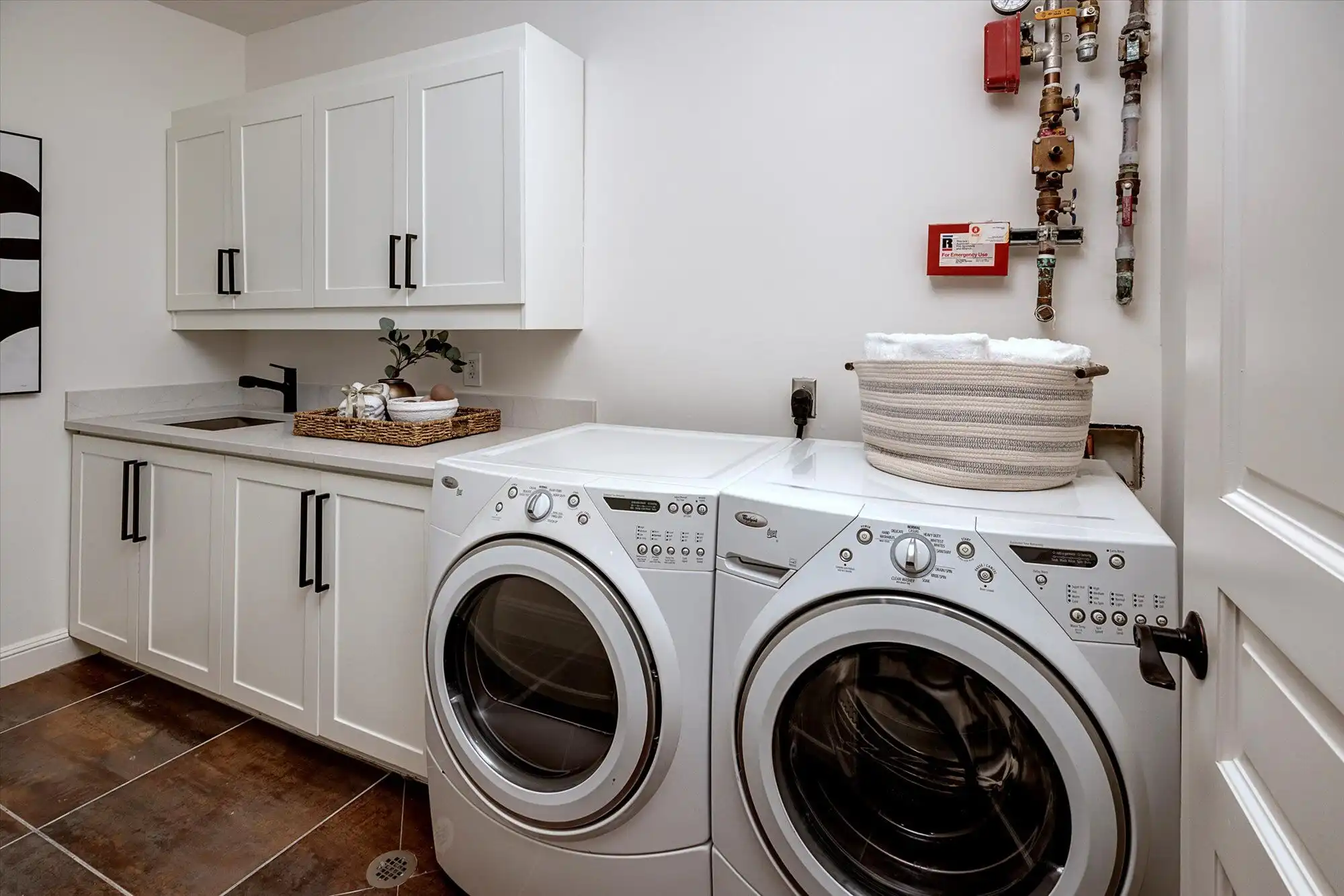 Modern laundry room with white cabinets and front-loading washer and dryer.