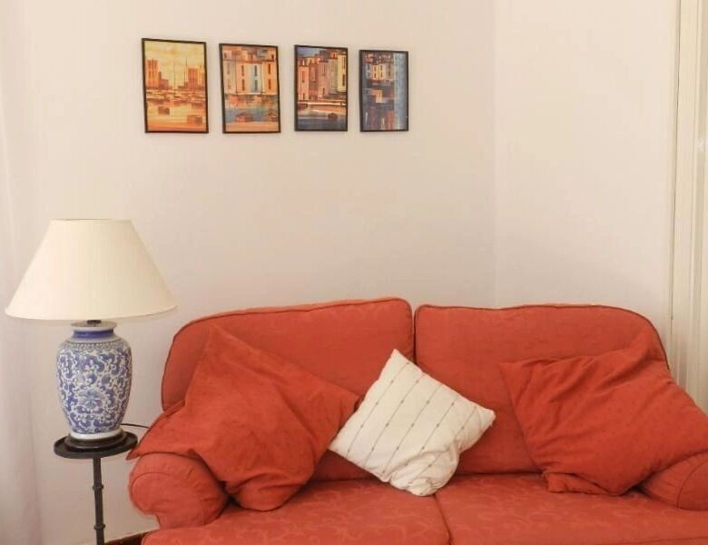 Villa interior featuring a red sofa, white pillow, and framed artwork on the wall in Arles-sur-Tech.