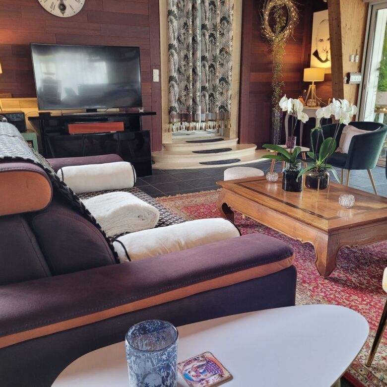 Spacious living area featuring stylish furniture, a large TV, and natural light from windows.