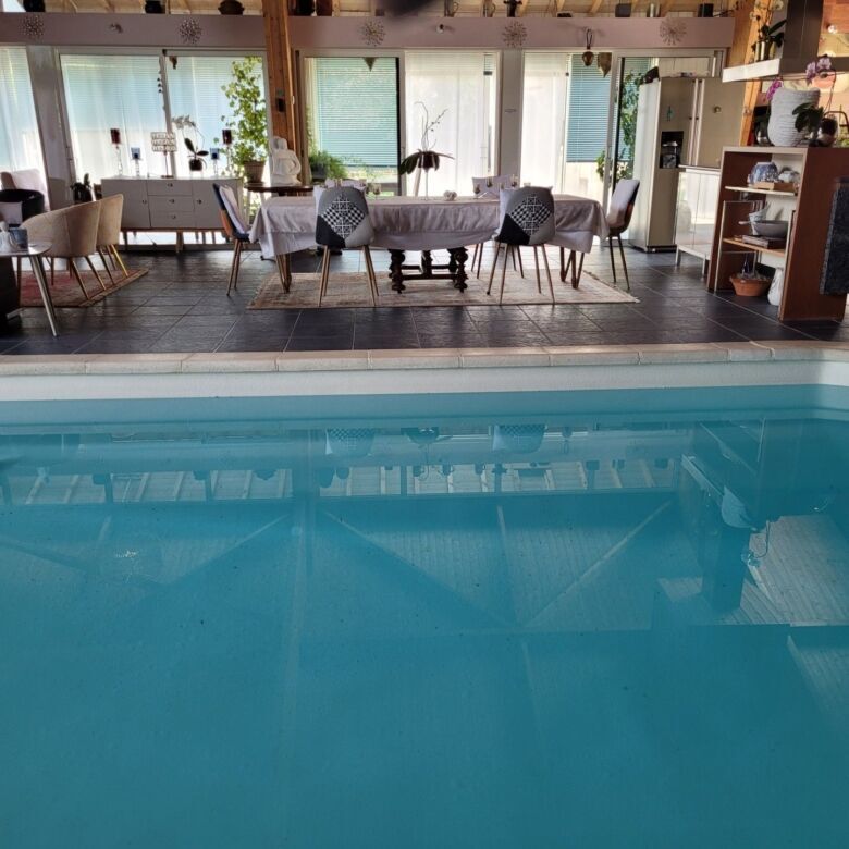 Indoor pool with surrounding lounge and dining area in a modern, stylish residence.