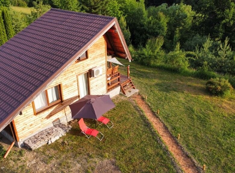 Cozy 1-bedroom log cabin for sale in Grozăvești surrounded by lush greenery.