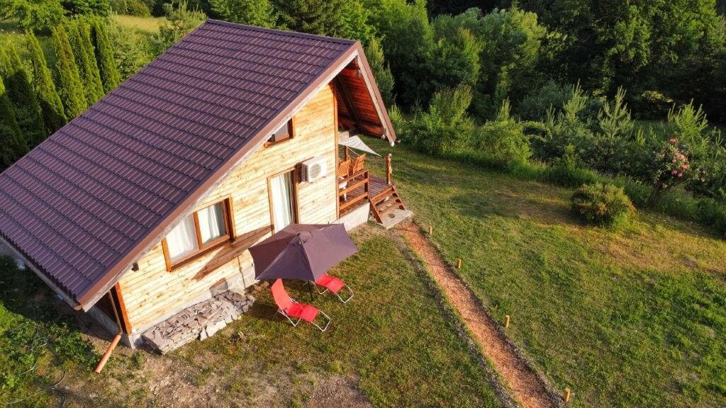 Cozy 1-bedroom log cabin for sale in Grozăvești surrounded by lush greenery.