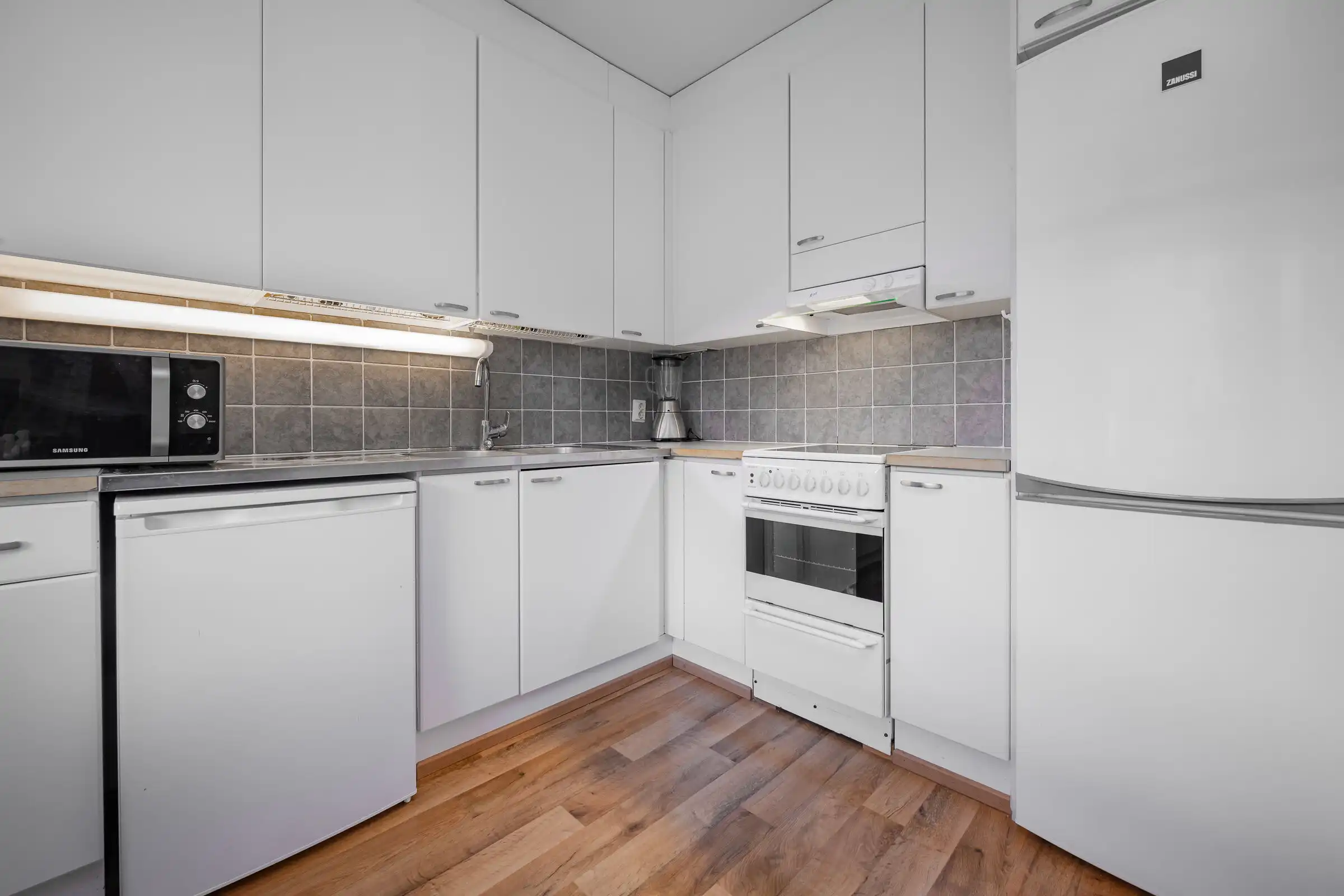 Bright, minimalist kitchen featuring white cabinets and essential appliances in Serene Hirvensalo Tu.