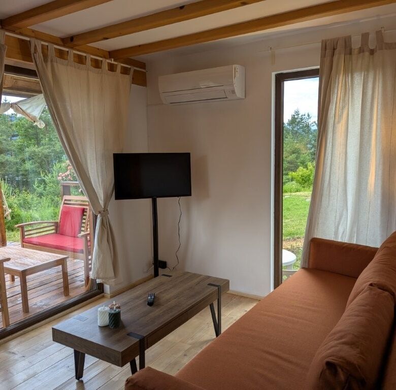 Cozy log cabin living room with large windows, outdoor view, and modern amenities in Grozăvești.