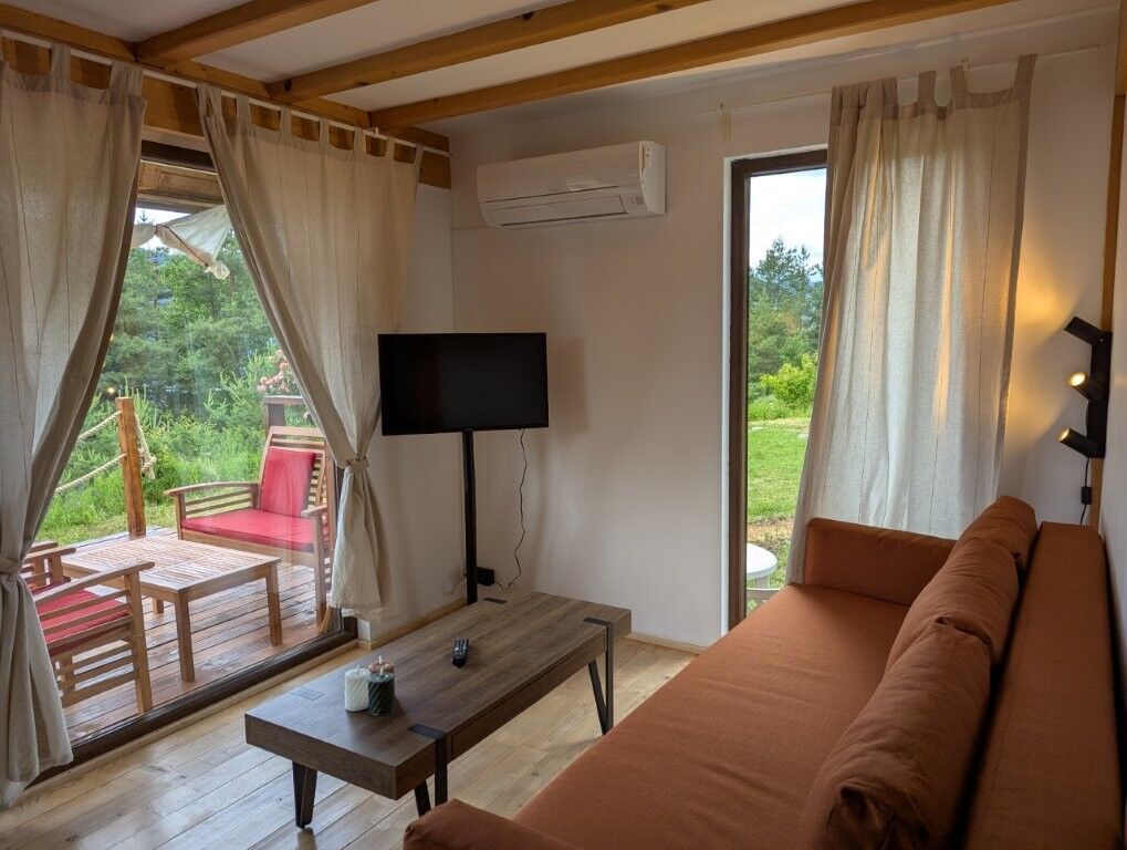 Cozy log cabin living room with large windows, outdoor view, and modern amenities in Grozăvești.