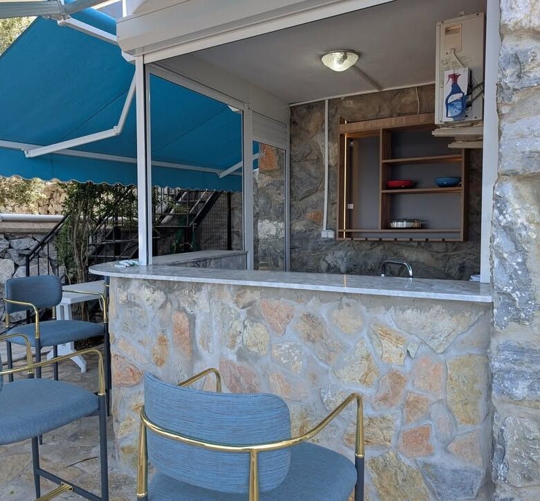 Outdoor bar with stone facade, seating, and blue awning for relaxing gatherings.
