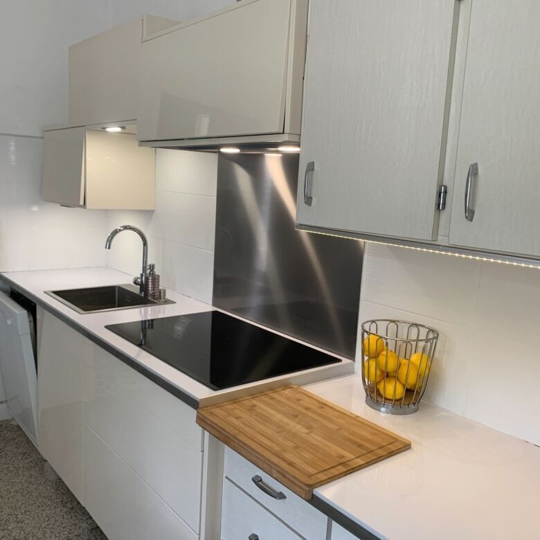 Modern kitchen with white cabinets and black countertop in Arles-sur-Tech.