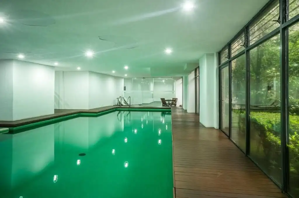 Indoor swimming pool in a luxury Mexico City apartment with large glass windows and modern design.