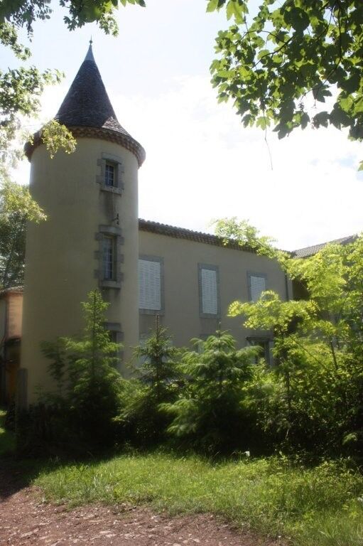 Chateau de Montcru with a turret, set in lush greenery in Allières Ariège.