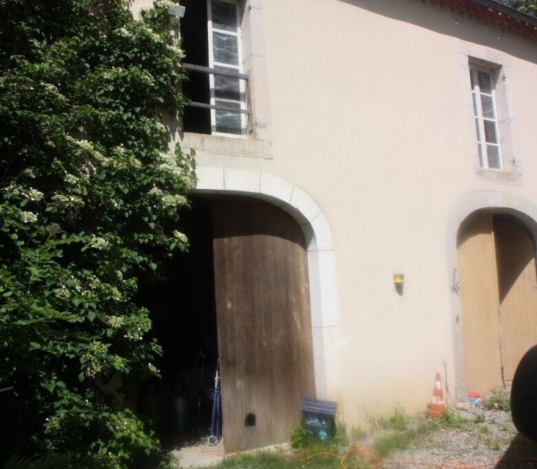 Chateau de Montcru with wooden doors and surrounding greenery in Allières, Ariège.