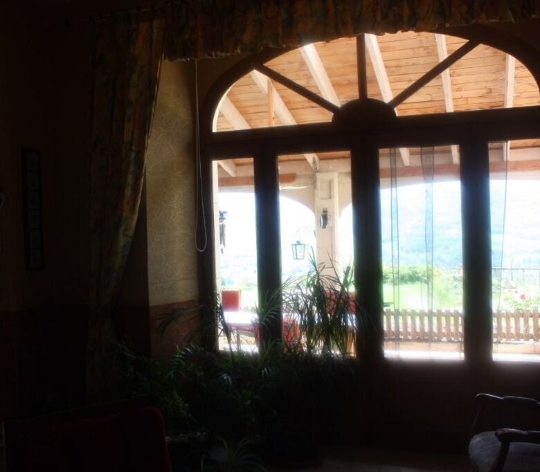 Elegant interior view of Chateau de Montcru with large arched window and scenic outdoor landscape.