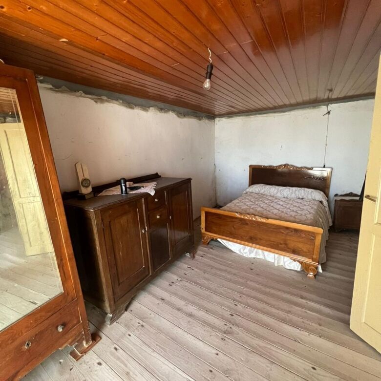 Comfortable bedroom with wooden ceiling and flooring, featuring a bed and vintage furniture.