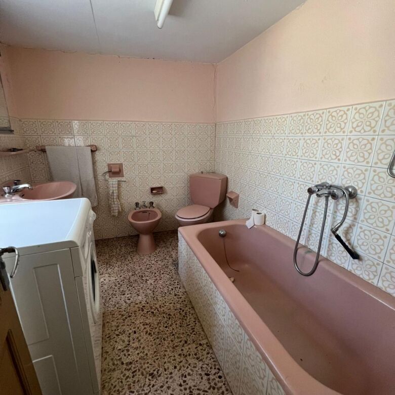 Bathroom with pink bathtub and vintage fixtures.