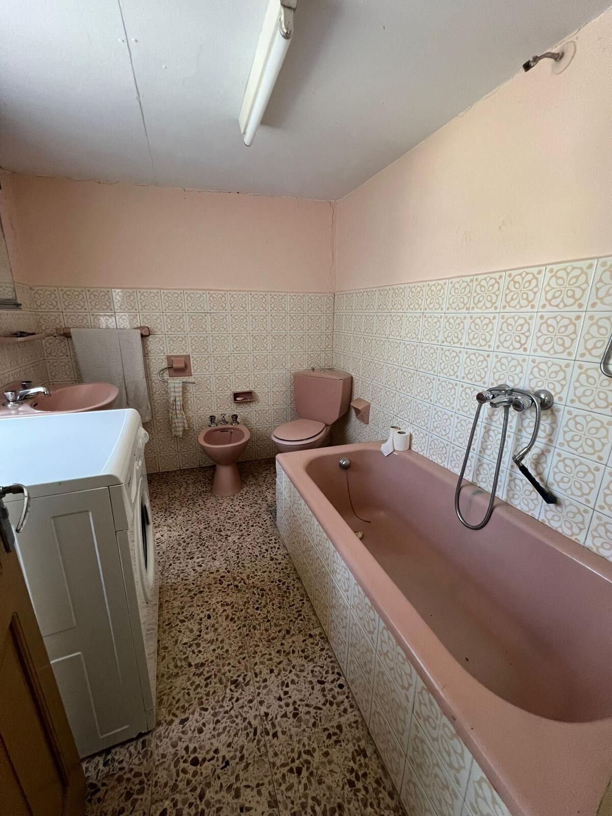 Bathroom with pink bathtub and vintage fixtures.