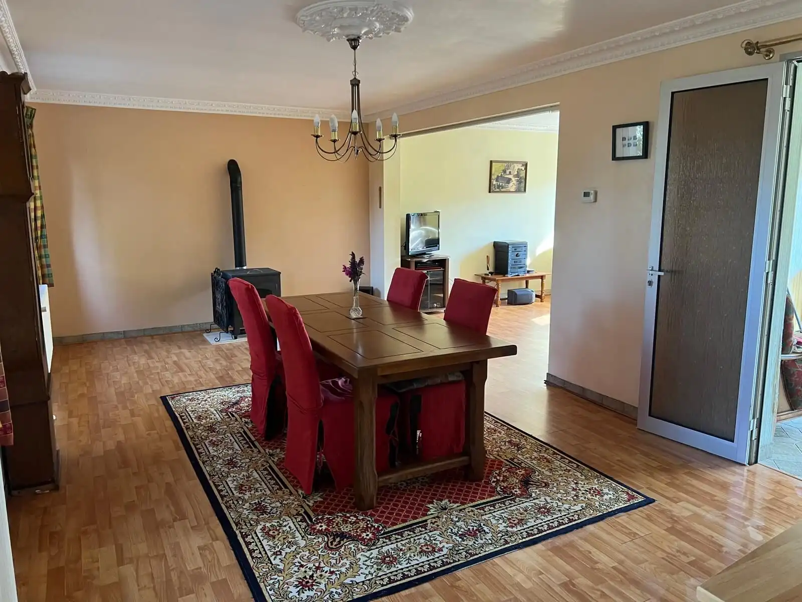 Spacious dining area with a wooden table and red chairs in a charming Vautorte home.