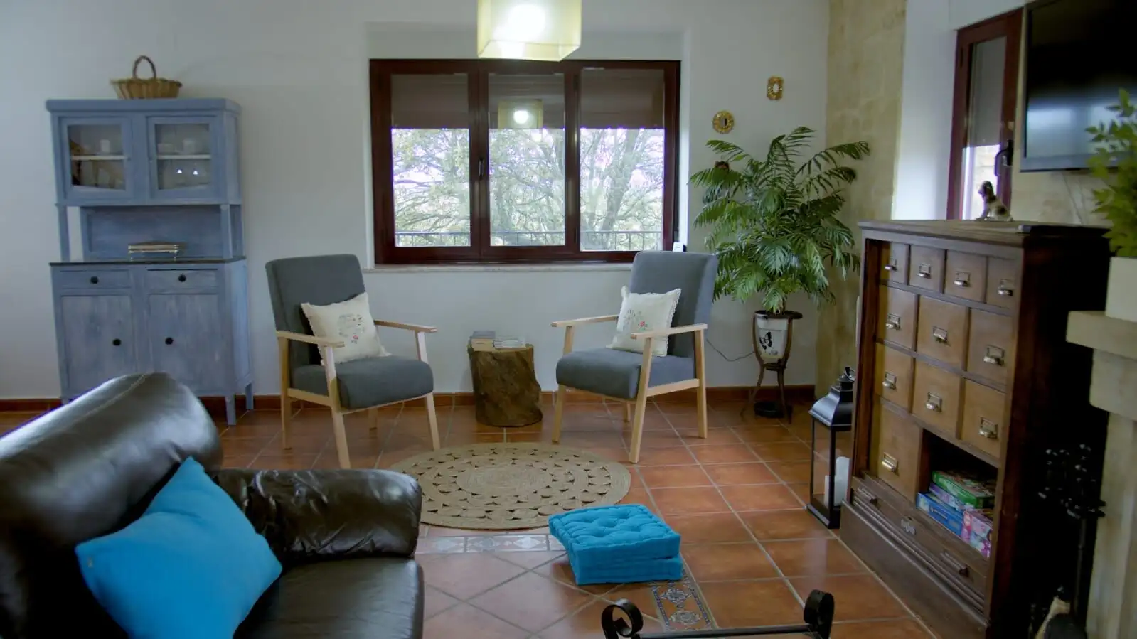 Cozy living room featuring rustic furniture, large window, and natural light in a charming Salamanca.