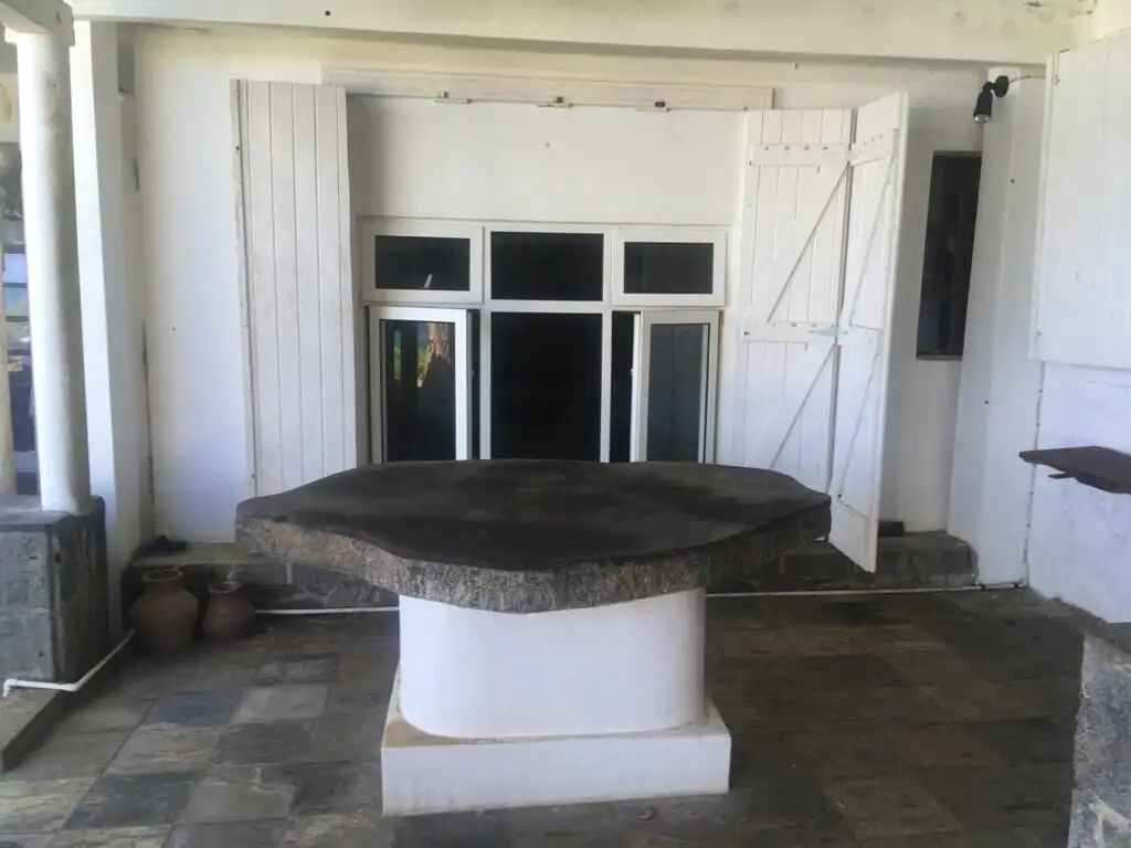 Seaside Luxury Living in Mauritius Elegant outdoor dining area with a large stone table and white wooden walls.