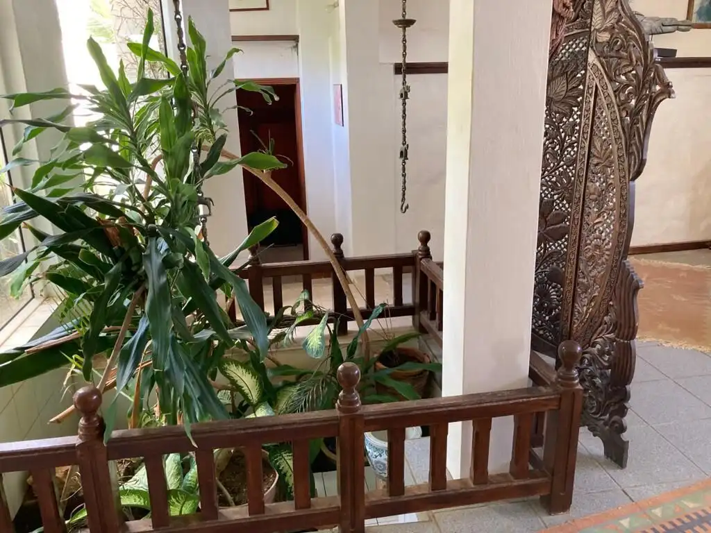 Seaside Luxury Living in Mauritius Elegant wooden balcony railing with lush green plants and traditional decor.