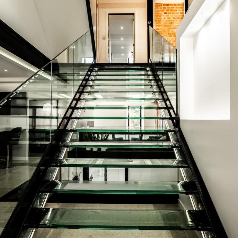 Elegant glass staircase leading to upper floors of a boutique hotel in Leiria.