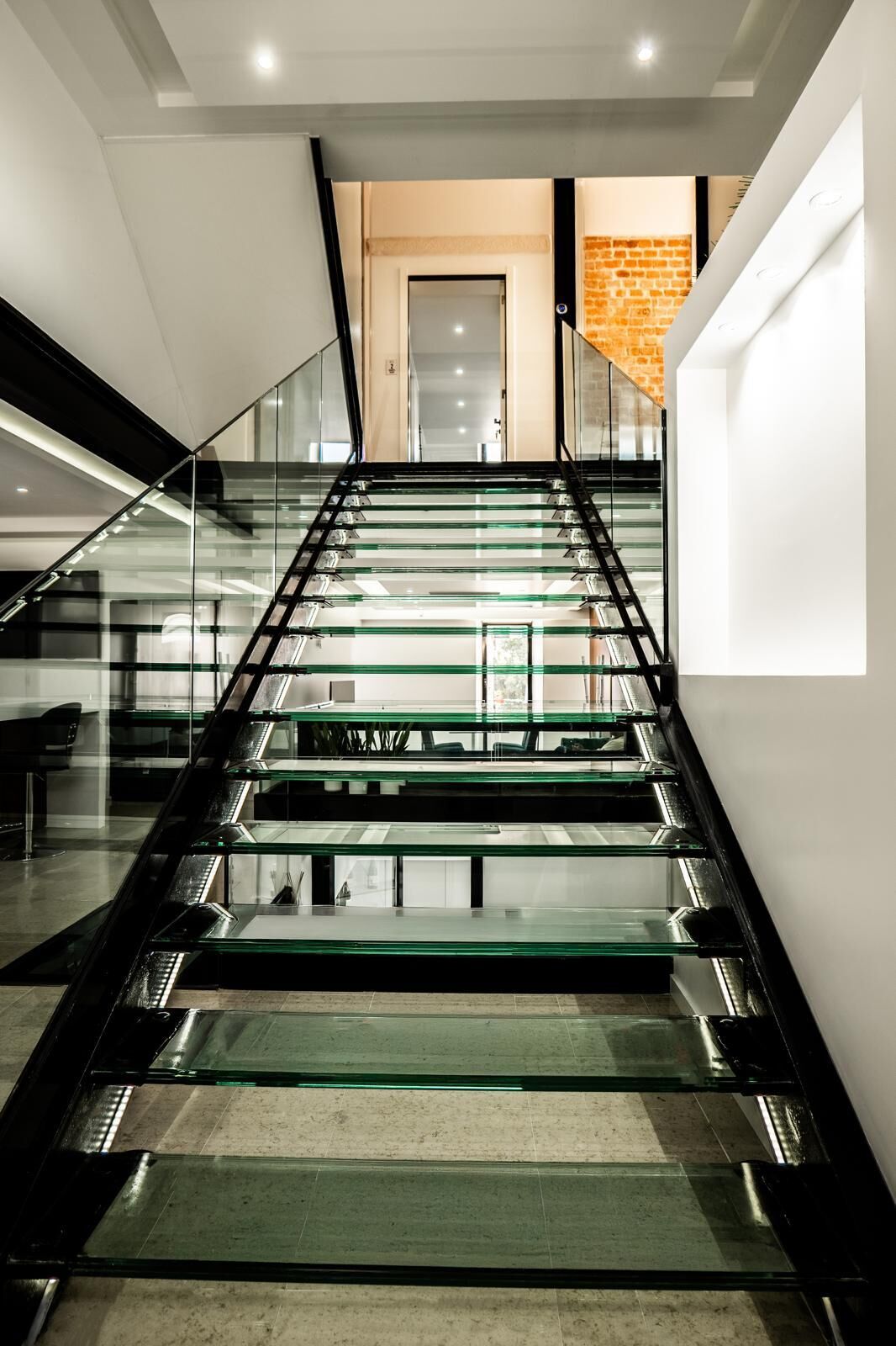 Elegant glass staircase leading to upper floors of a boutique hotel in Leiria.