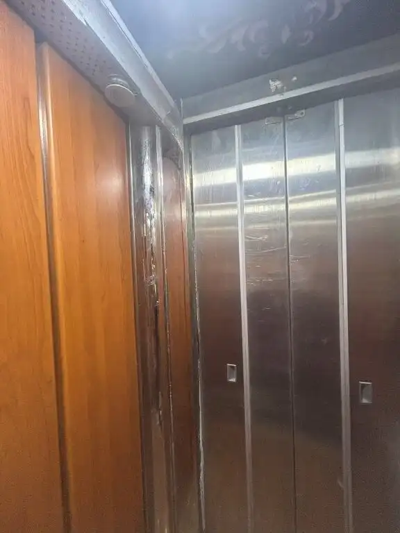 Elevator interior with modern stainless steel doors and wooden paneling.