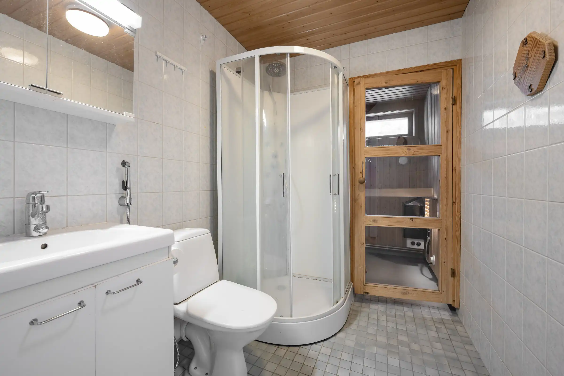 Bathroom with shower, toilet, and sink in a cozy Finnish home.