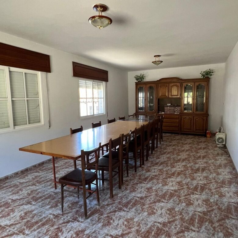 Bright and airy dining area with a large wooden table and chairs in a charming Taboada Galicia home.