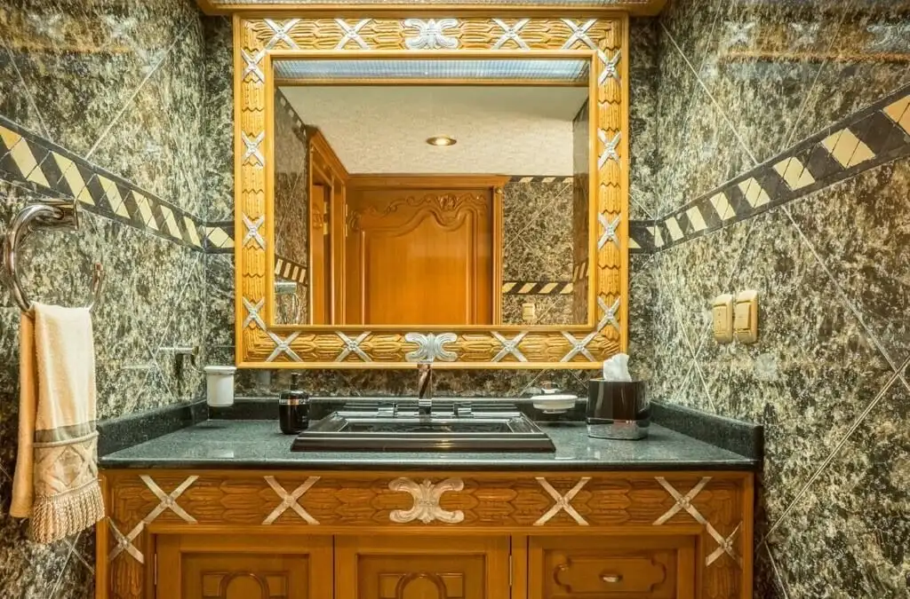 Elegant bathroom with marble walls and wooden accents, featuring a large mirror and modern fixtures.