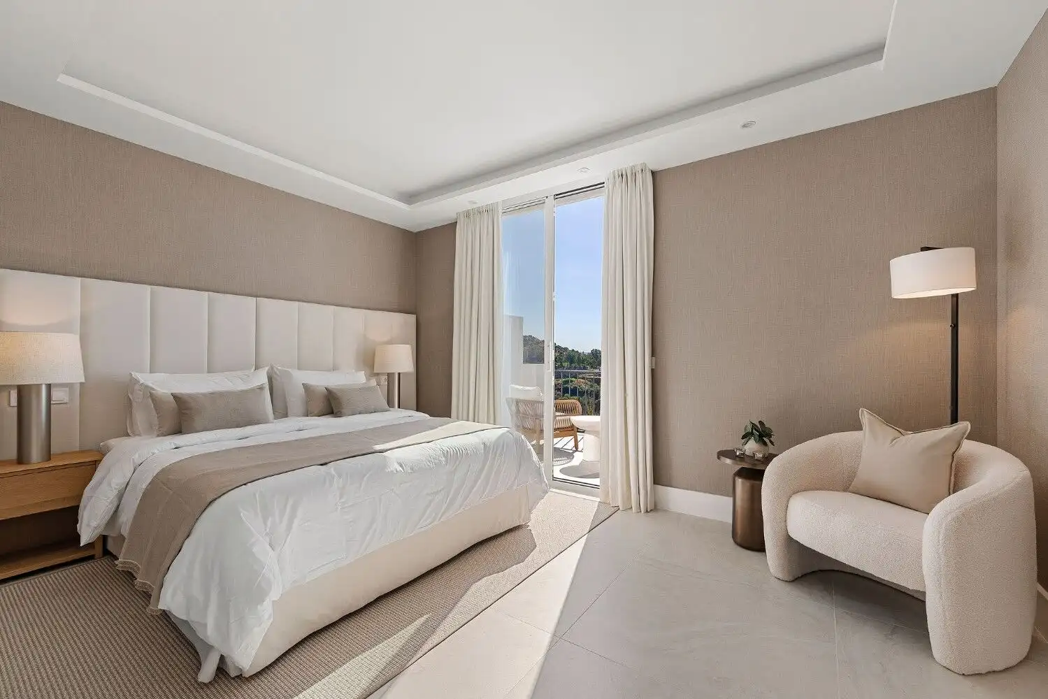 Luxurious bedroom featuring contemporary decor and a private balcony overlooking scenic surroundings.