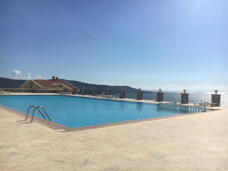 Poolside view of the luxurious 3-bed duplex apartment at Pearl Rock Retreat, Akbuk Didim, with stunn.