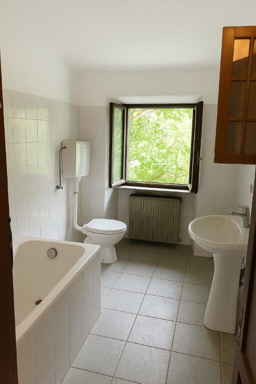 Bright bathroom with window and classic fixtures in Mezzana Mortigliengo Piedmont.